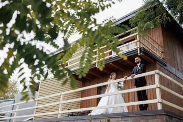 Couple enjoying their wedding day on balcony of beautiful wooden house in nature setting