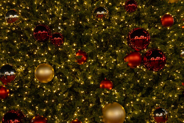 Full view of a Christmas tree decorated with glowing lights and red-gold ornaments creating a festive, vibrant scene.