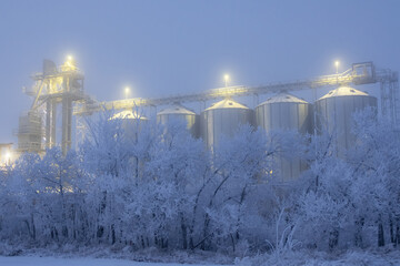 Naklejka premium Lights on grain elevator storage in foggy winter night.