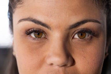 Female highlighting hazel eyes while framing contours in studio, showcasing gold stud earrings