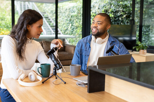 Diverse coworkers adjusting microphones while recording podcast at home office with laptop - Powered by Adobe