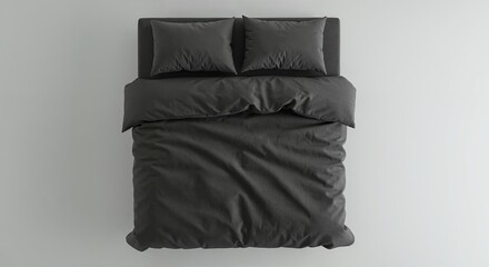 A neatly made bed with dark grey duvet and two matching pillows rests on a light background, viewed from directly above, offering clean copy space.