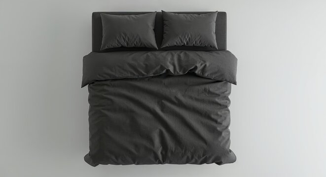 A neatly made bed with dark grey duvet and two matching pillows rests on a light background, viewed from directly above, offering clean copy space.