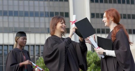 Woman receiving diploma and cap from red-haired female friend marking graduation on campus quad