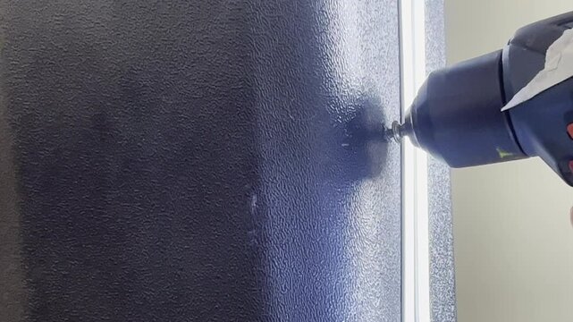 Close-up of an electric screwdriver in reverse mode removing a screw, showing precise tool control, torque and smooth extraction during a mechanical task.