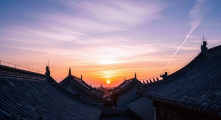 A view of traditional Chinese rooftops silhouetted against a vibrant sunset sky. The image captures the architectural detail and the beauty of the natural light
