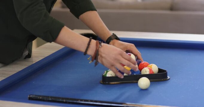 Person approaching pool table, racking balls, removing red stripe then releasing rack to start game