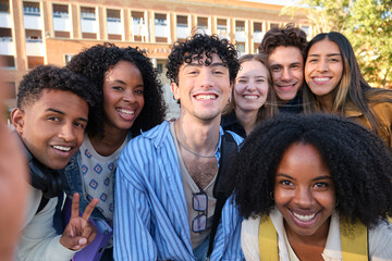 Diverse group of happy university students smiling at camera, taking a selfie together on campus