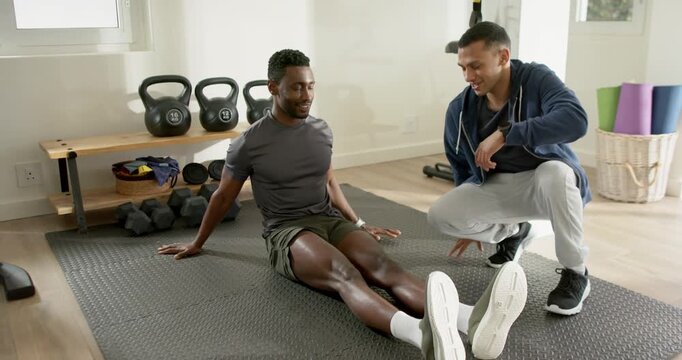 Coach guiding African American man performing foot drags and knee lifts for strength in home gym