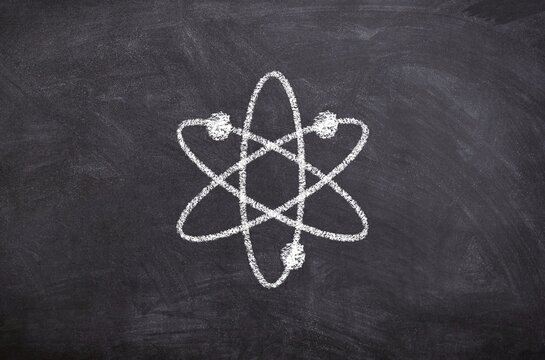 Hand drawn chalk sketch on blackboard atom symbol symbolizing science technology energy and research