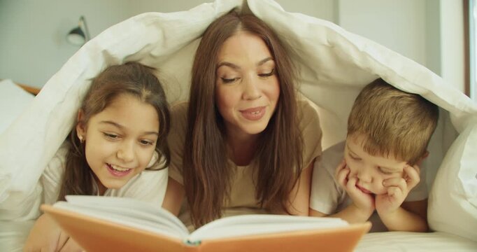 Family bedtime joy, Mom recounts tales as kids smile and play happily