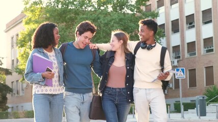 Group of four smiling multiracial friends walking together after class at the university campus