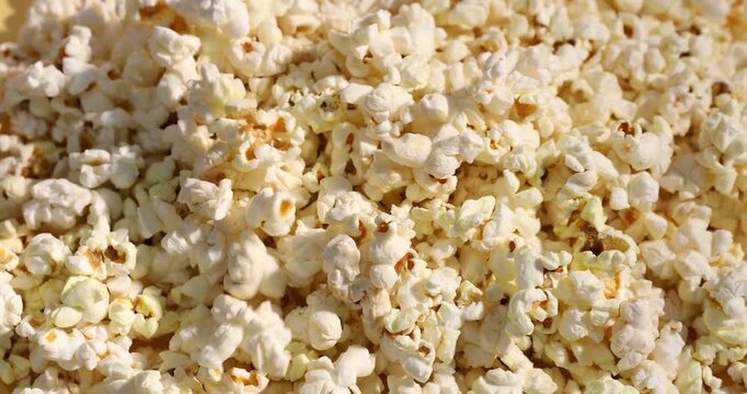 Pouring tasty popcorn on pile, closeup view