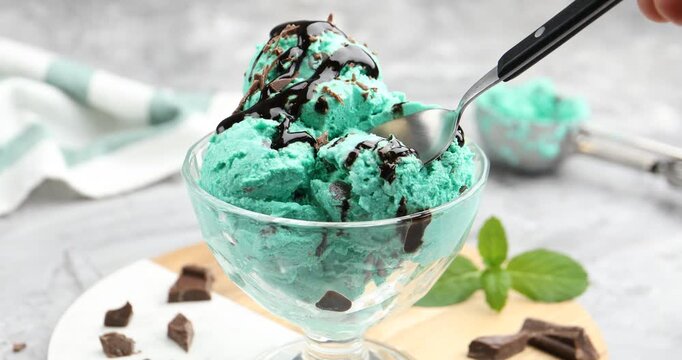 Woman eating tasty mint chocolate chip ice cream at table, closeup