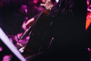 Concert view of contrabass violoncello player with vocalist and musical band during string concert, jazz orchestra performing music, violoncellist cello jazz player on stage in club, music arena hall