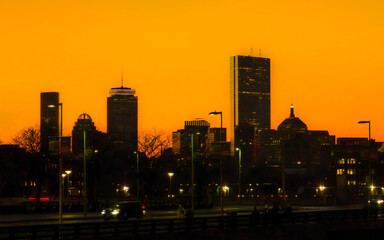 Boston city skyline at sunset with illuminated modern buildings glowing with vibrant colors in Massachusetts, USA, a vibrant metropolitan landscape of atmosphere and reflection.