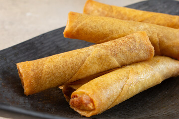 A closeup view of a pile of lumpia, on a plate.