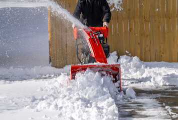 man removing snow on the driveway of the house by snow blower