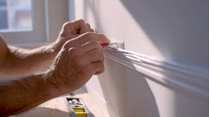 Handyman securing cable management system along a wall at home