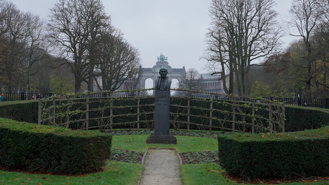 BRUSSELS, BELGIUM - NOVEMBER 26, 2025 - Robert Schuman bust stands in Parc du Cinquantenaire looking towards the Triumphal Arch