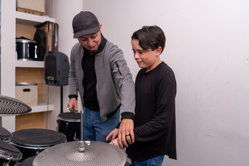 Teacher adjusting the student’s hand and wrist while holding drumsticks during a drums lesson....