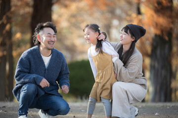 A family playing in an autumn park A parent and child smiling for a commemorative photo in a forest of autumn leaves Images of heartwarming memories from outings and leisure activities