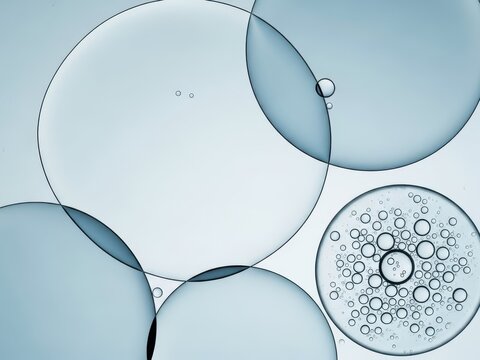 Abstract macro view of overlapping translucent blue liquid spheres and small bubble formation representing science, chemistry, or cosmetic serum texture