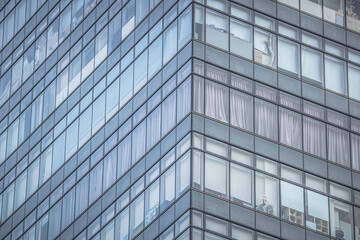 Fototapeta premium A modern high-rise building with a glass facade and a whimsical Popeye image in one window, contrasting corporate architecture with playful detail.