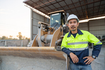 A construction manager poses confidently beside a wheel loader, overseeing the raw material aggregate operations at a small ready-mix plant.