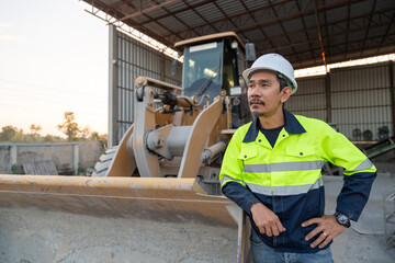 A construction manager stands next to a wheel loader, overseeing aggregate operations and industrial machinery at a ready-mix plant.