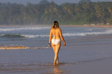 Young Woman in Swimming Suite is Walking Along the Shoreline at Talalla Beach, Sri Lanka