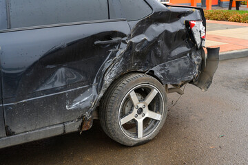 Rear end damage to a black car in a parking lot after a collision