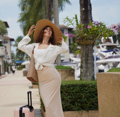 Young woman with luggage walks near the boat marina