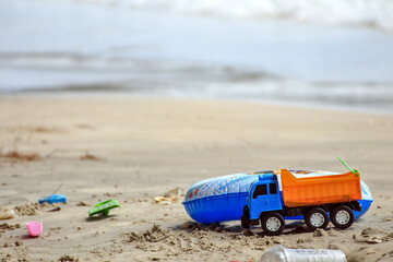 Toy truck with colorful rubber rings and sand toys on the beach by the sea