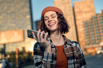 Fototapeta premium woman smile with smartphone in city street at golden hour, candid lifestyle portrait showing authenticity and emotional storytelling, mindful living vibe with warm golden glow.