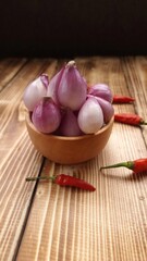 Red onion in a wooden bowl and chilies in rustic table 