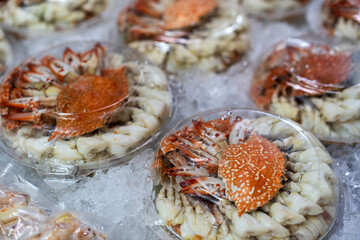 fresh crab or horse crab and steamed peeled blue swimming crab in plastic box and ice tray by ready to eat for sale and freezer frozen seafood in street food market or restaurant in thailand