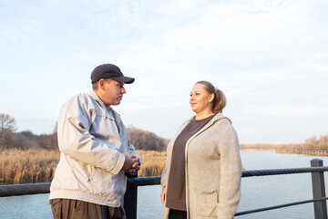 Casual middle-aged woman enjoys a coffee break while walking in park.