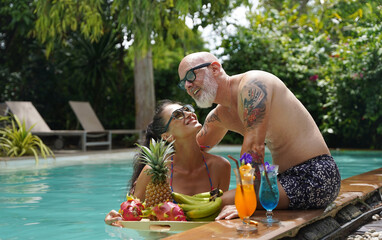 A man and woman with cocktails in a swimming pool