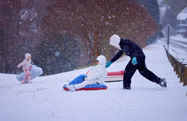 Children Sledding Down a Snowy Hill &ndash; Winter Fun in Motion under Soft Falling Snow. Active Family Snow Day