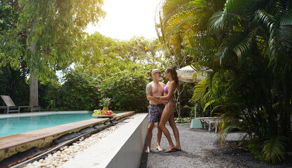 A man and a woman joyfully walking in front of a beautiful pool