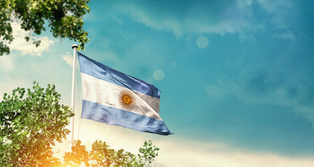 Argentina national flag waving in the sky behind the tree. The flag blowing with beautiful sunlight. Argentina national flag for independence day.
