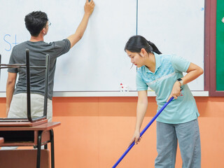 Asian teacher woman cleaning classroom at school. People clean housework college. Back to school. Education knowledge learning. Chore of student 