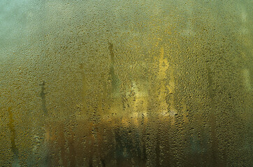 misty window showing blurry view of trees and buildings. condensation on glass creates soft, abstract pattern, blurring outdoor. foggy window reveals indistinct landscape with trees and structures.