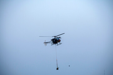 Silhouette helicopter is flying on isolated blue sky