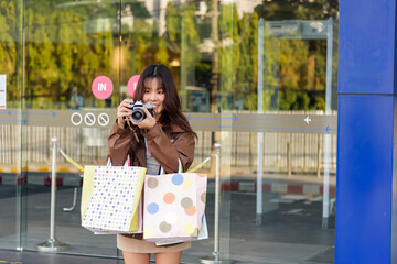 Asian woman shopping for fashion, bags, enjoying lifestyle, people shop at city mall, preparing for black friday, capturing moments with retro camera