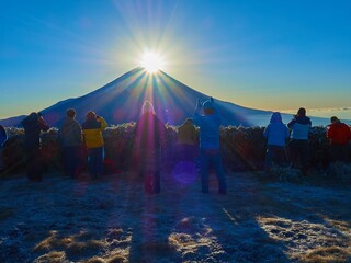 冬の朝の山梨県富士河口湖町 竜ヶ岳山頂からダイヤモンド富士を眺める登山者