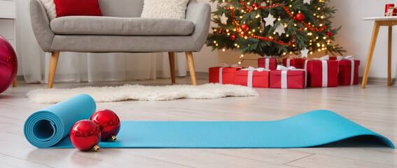 Blue yoga mat unrolled on wooden floor in a cozy festive room, soft Christmas lights and ornaments create a warm, serene holiday atmosphere.
