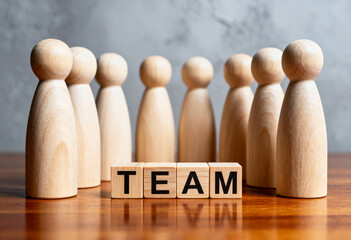 Wooden people figures stand in a semicircle with word team on blocks, concept for business, teamwork, and unity