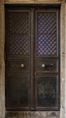 Classic wooden double door with decorative panels and vintage handles, framed by marble walls, showcasing traditional architecture and elegant historic craftsmanship.